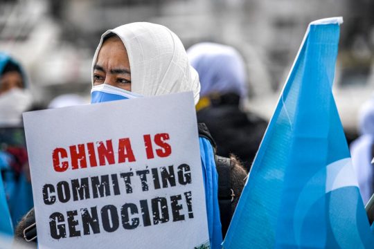 A veiled protester holds a sign that reads 